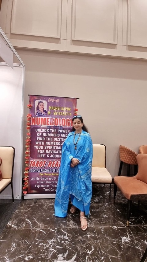 Madhvi Oberoi Kapur, professional tarot reader, numerologist, and spiritual healer standing next to her Tarot and Numerology banner